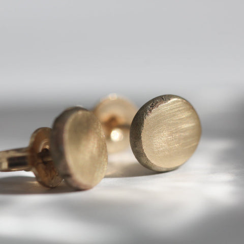 Close-up of a pair of gold earrings on a light gray background