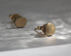 Pair of gold stud earrings on a reflective surface