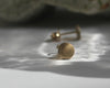 Gold stud earrings on a textured surface with a blurred background