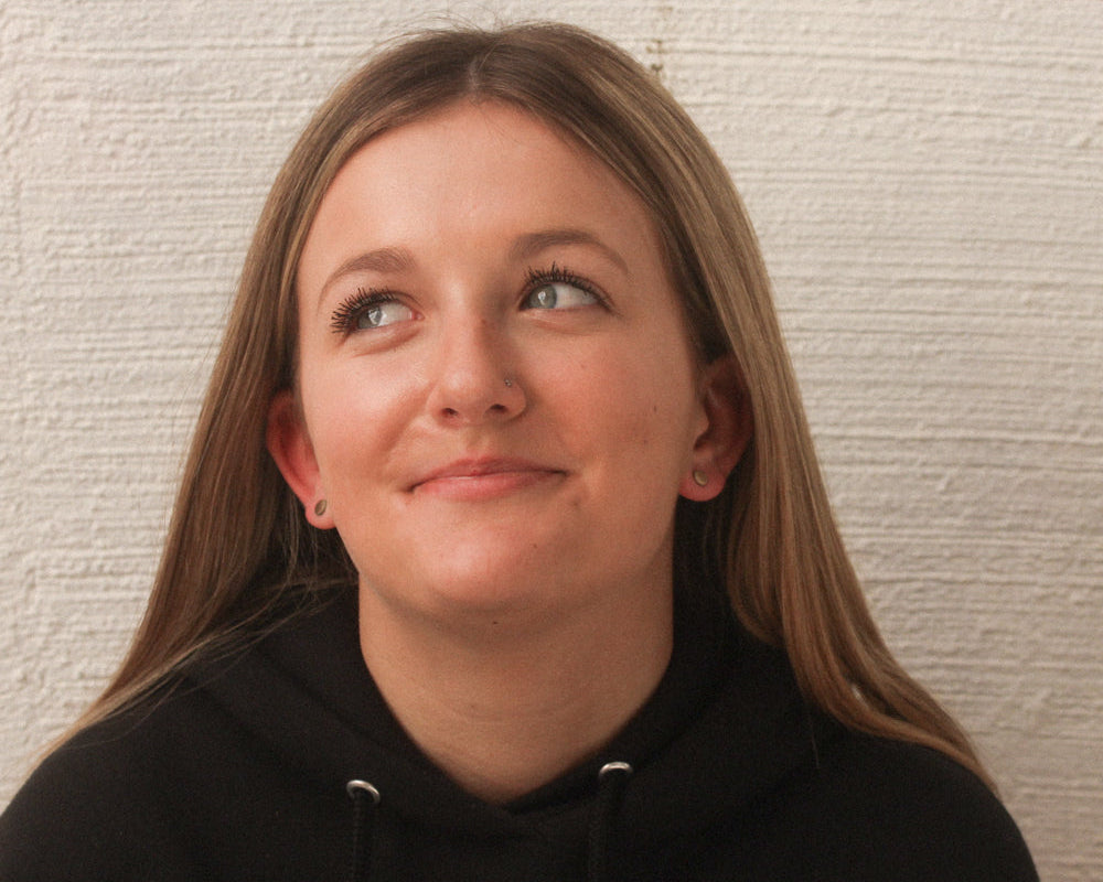 Person wearing a black hoodie against a textured beige wall